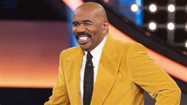Steve Harvey Flashes a White Smile While Wearing a Leather Jacket & Matching Olive Trousers
